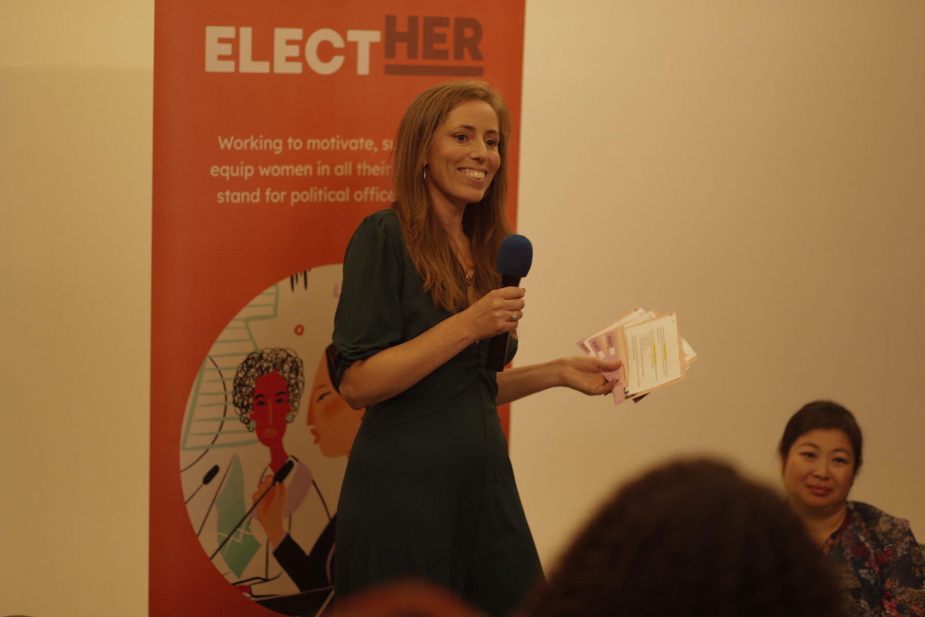  Elect Her CEO Hannah Stevens speaks into a microphone.